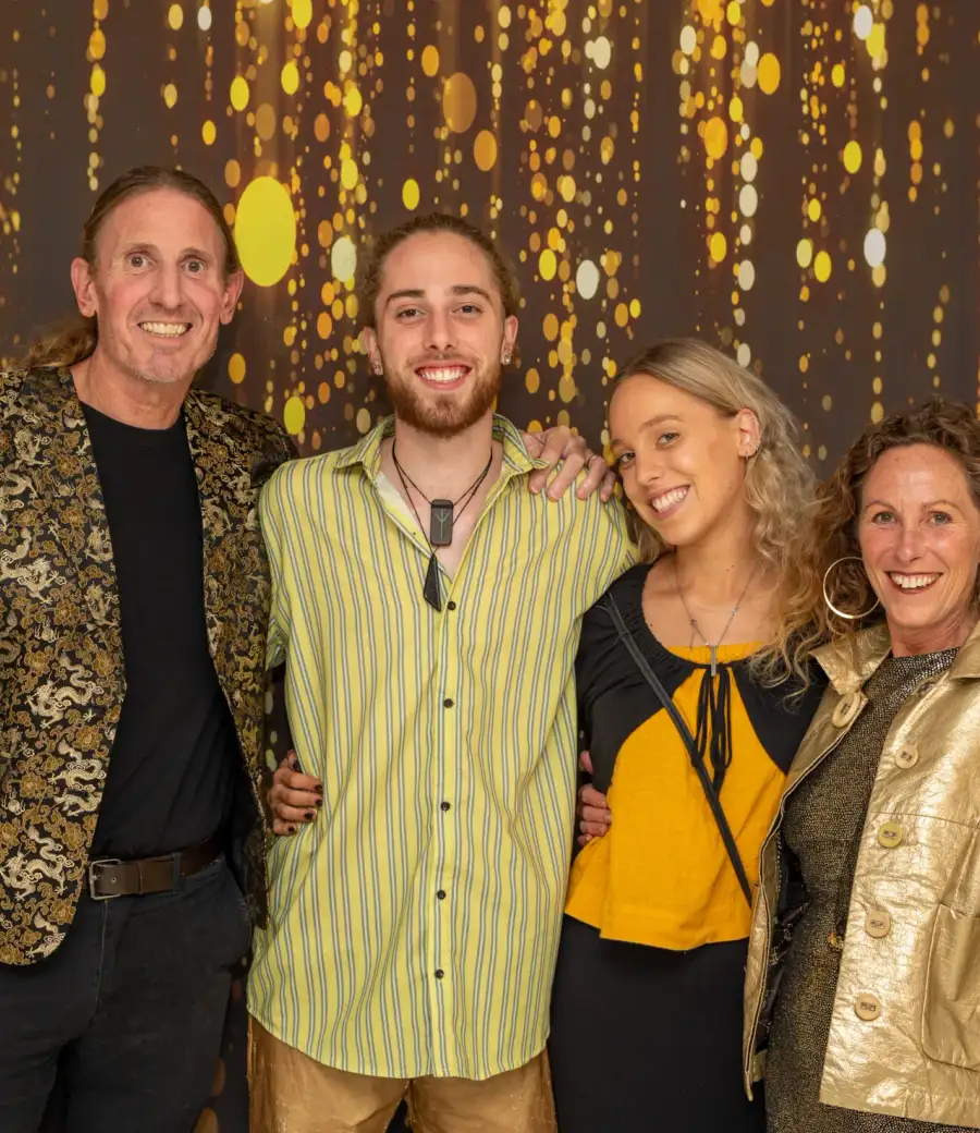 Guests posing together in front of a gold event backdrop