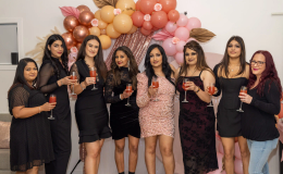 Guests posing together in front of a pink backdrop